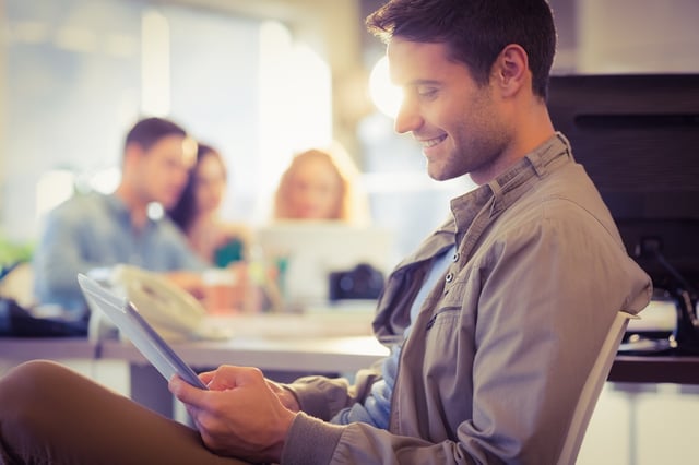 Smiling young man using digital tablet in the office.jpeg